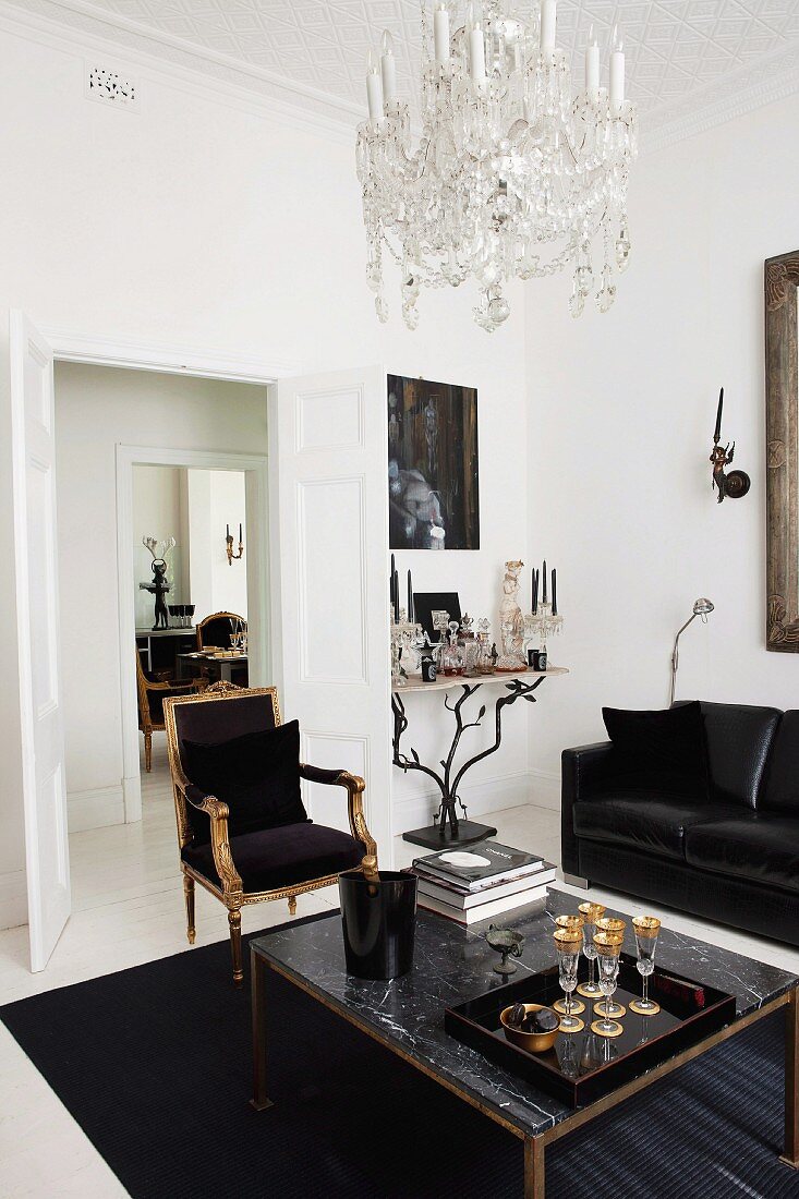 Elegant living room with glasses of champagne on marble table and leather sofa combined with gilt Renaissance chair