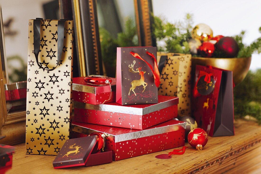 Geschenkpakete und Geschenktüten mit Weihnachtsdeko auf rustikalem Holztisch