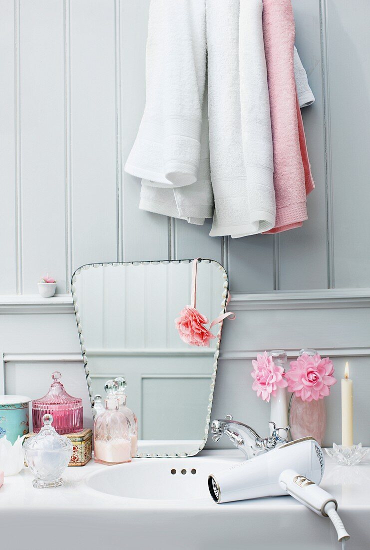 Retro-style hairdryer on washstand next to various bottles and mirror leaning on wooden wall