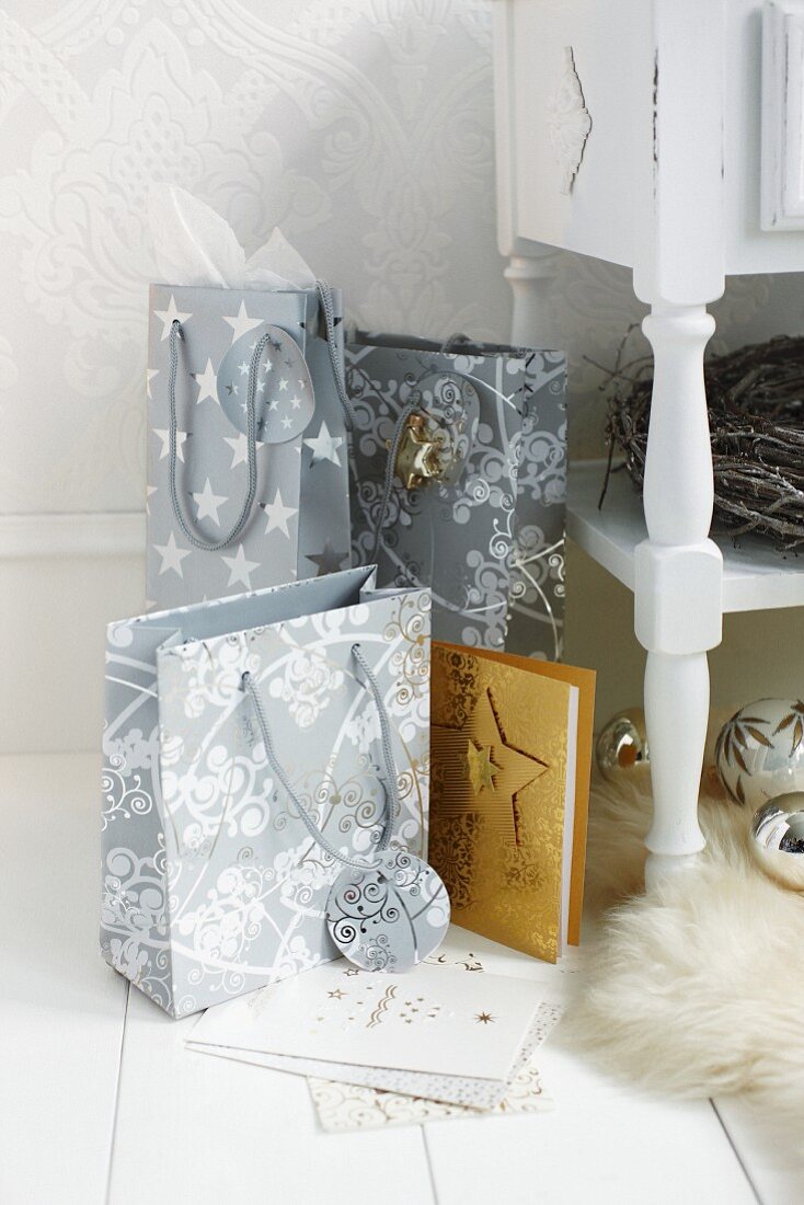 Gift bags with Christmas motifs on white wooden floor