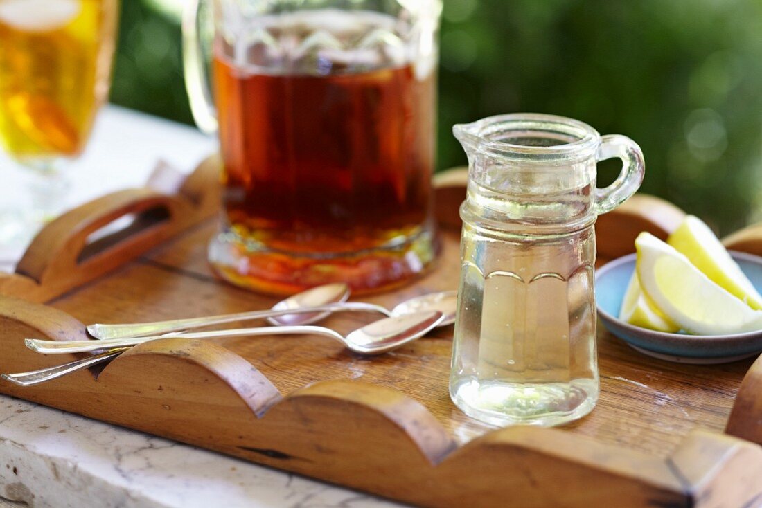 Small Glass Pitcher of Simple Syrup; Lemons and a Pitcher of Iced Tea; On a Tray Outdoors