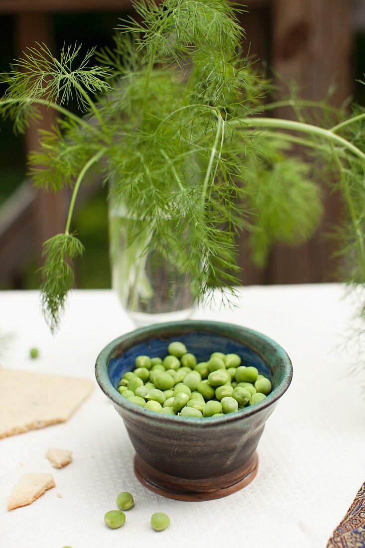 Peas in a small dish and dill in a glass