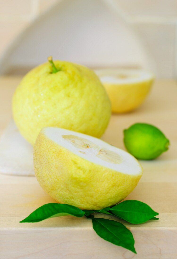 Lemons, whole and halved, with lemon leaves and a lime