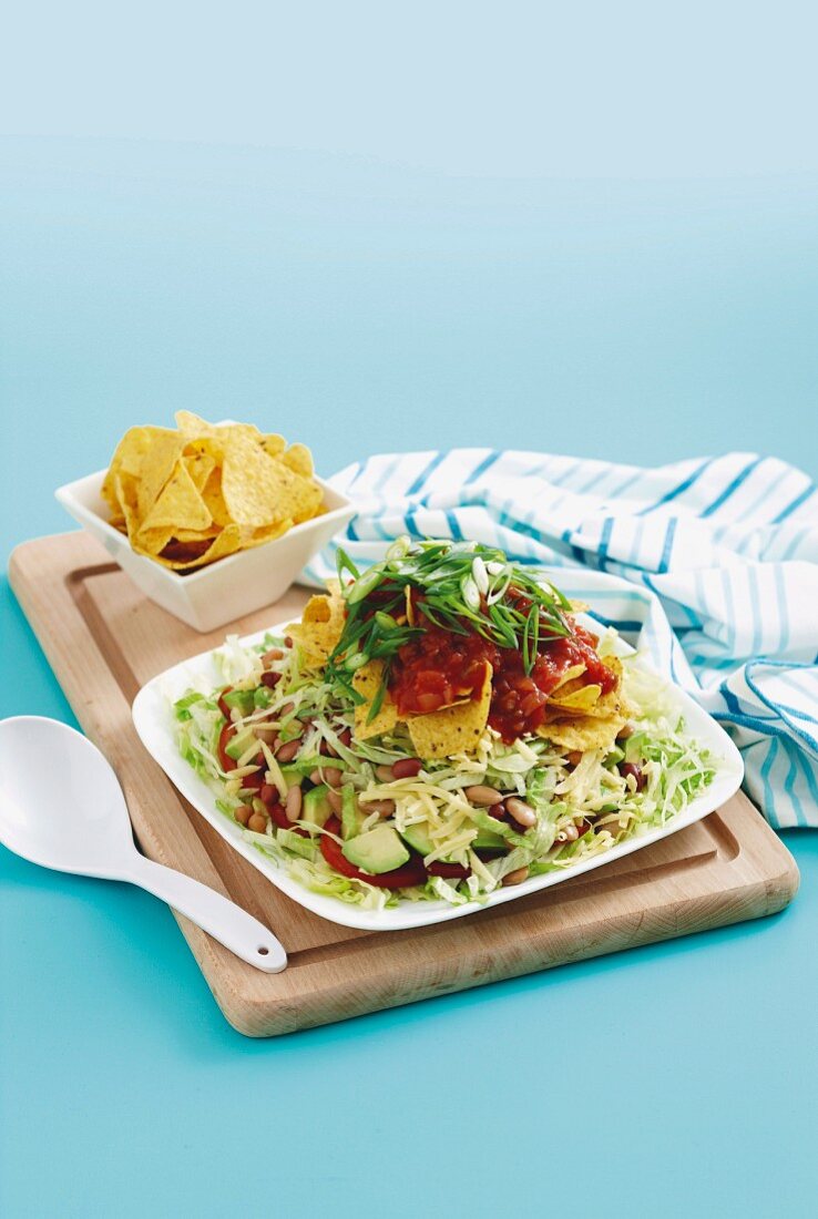 A layered salad with beans, avocado, tortilla chips and tomato salsa (Mexico)