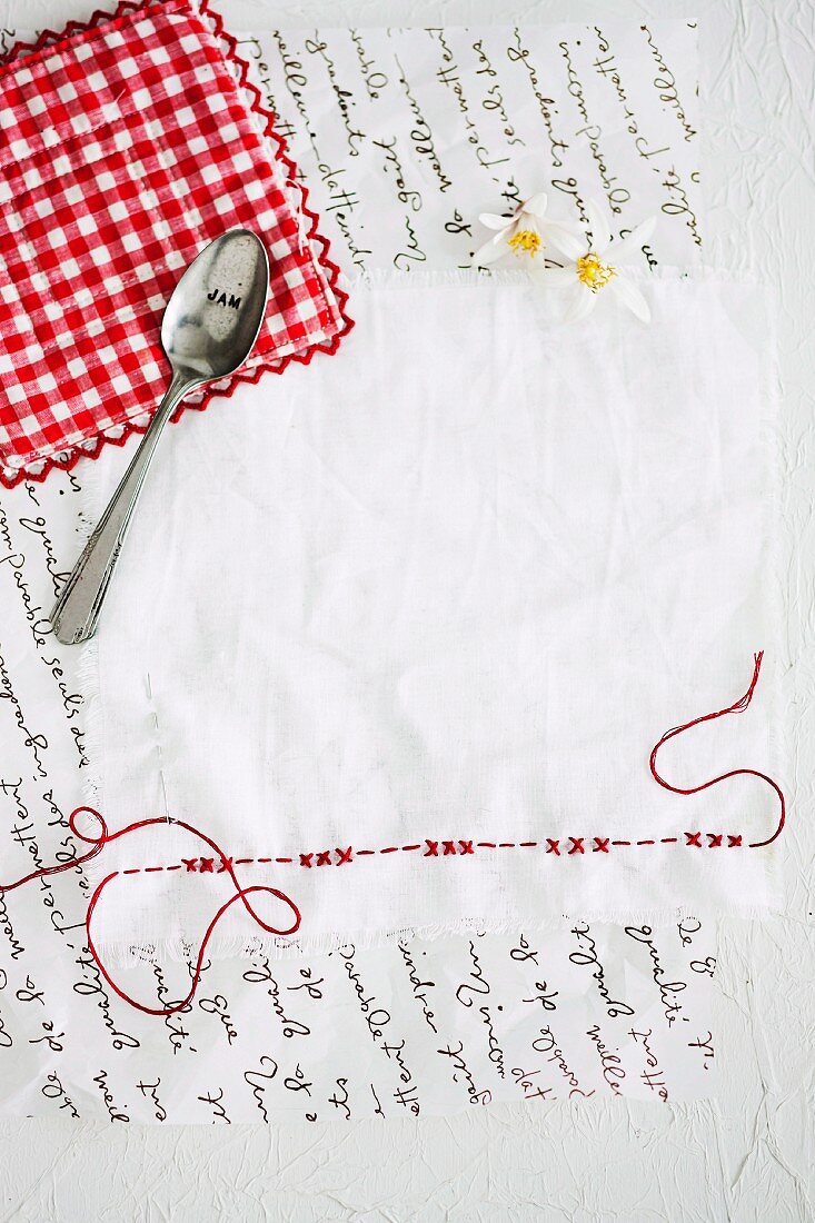 White napkin with red embroidery and jam spoon
