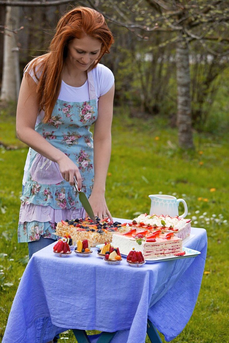 A young woman cutting a layer cake