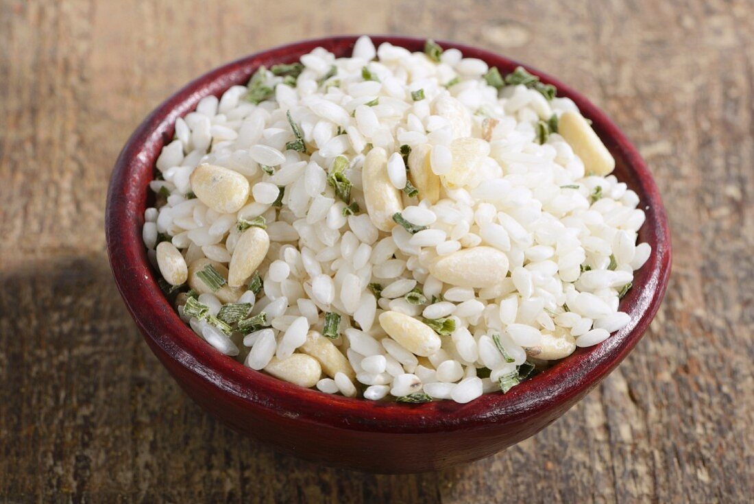 Vialone Nano risotto rice with pine nuts and chives in a ceramic bowl