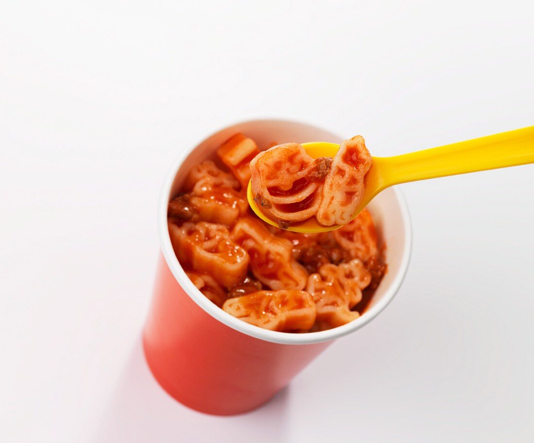 Pasta in bolognese sauce in a cup with a plastic spoon