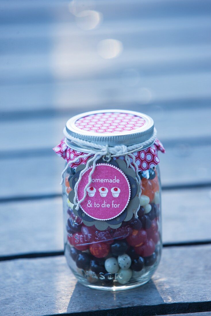 Assorted sweets (jelly beans, liquorice and chocolate drops) in a jar as a gift