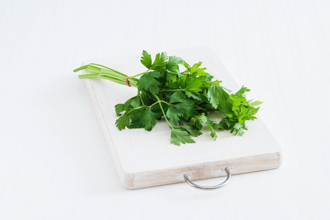 A bunch of flat leaf parsley on a chopping board