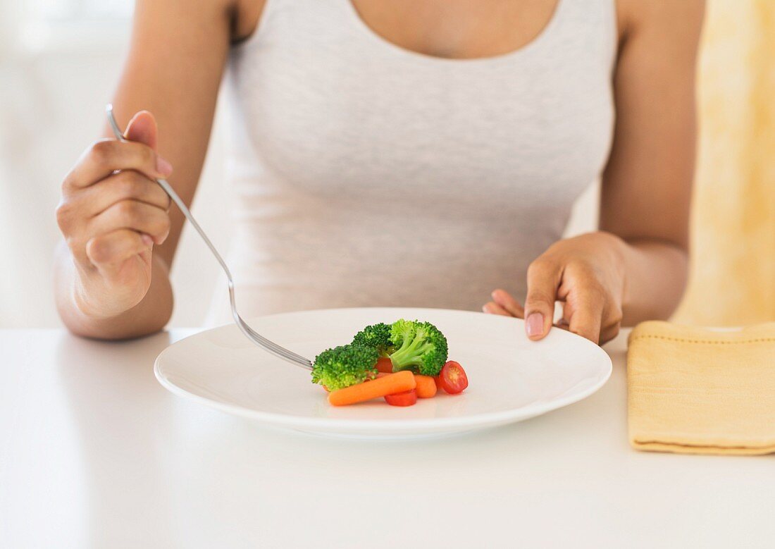 A young woman eating vegetables