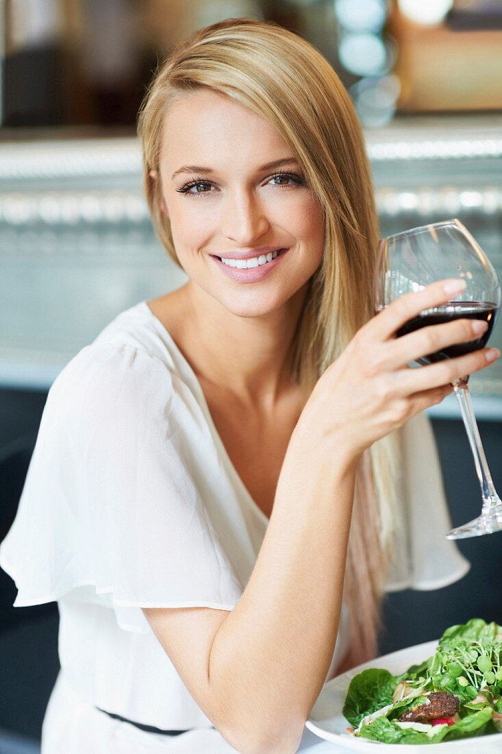 Frau trinkt ein Glas Rotwein beim Mittagessen im Restaurant