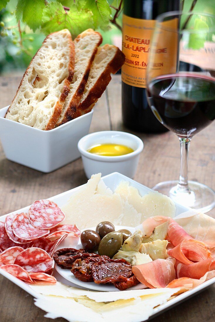 A plate of mixed starters, with bread and red wine