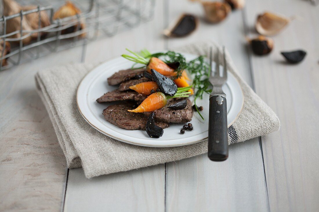 Beef fillet with baby carrots and black garlic