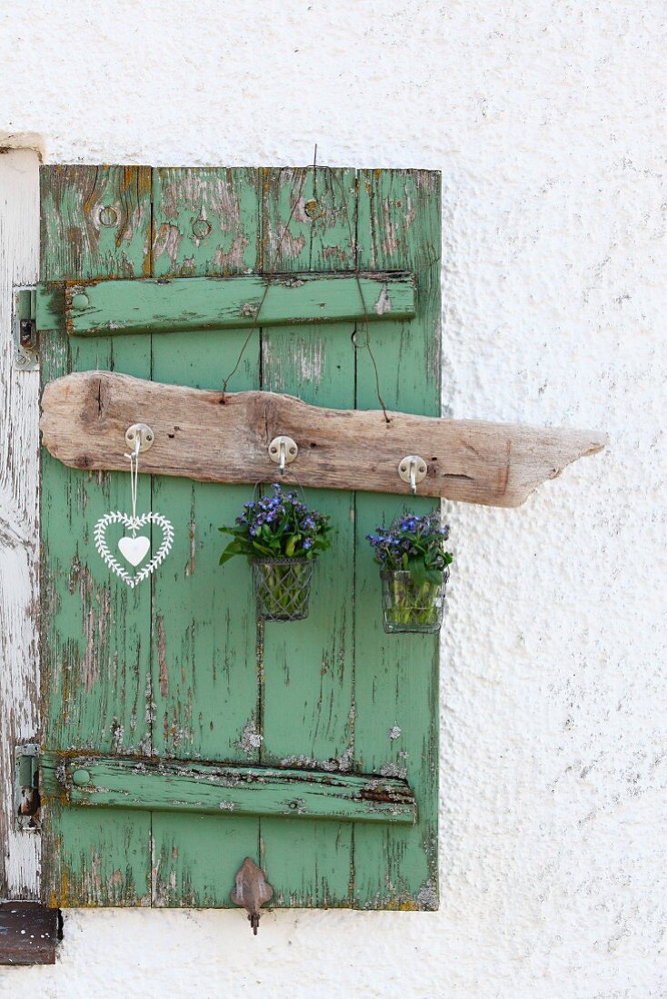 Hook rack made from old driftwood with posies of forget-me-nots and heart ornament hanging on vintage window shutter