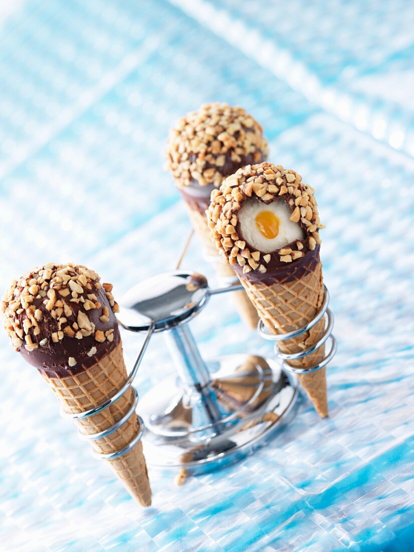 Vanilla ice cream in waffle cones with caramel sauce and chocolate and nut coating