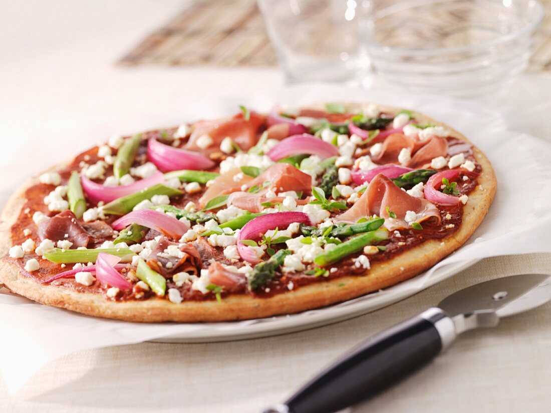 Pizza with green asparagus, ham and red onions