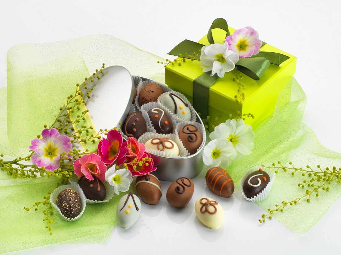 Easter chocolates in a tin with green tulle, primroses and a gift box