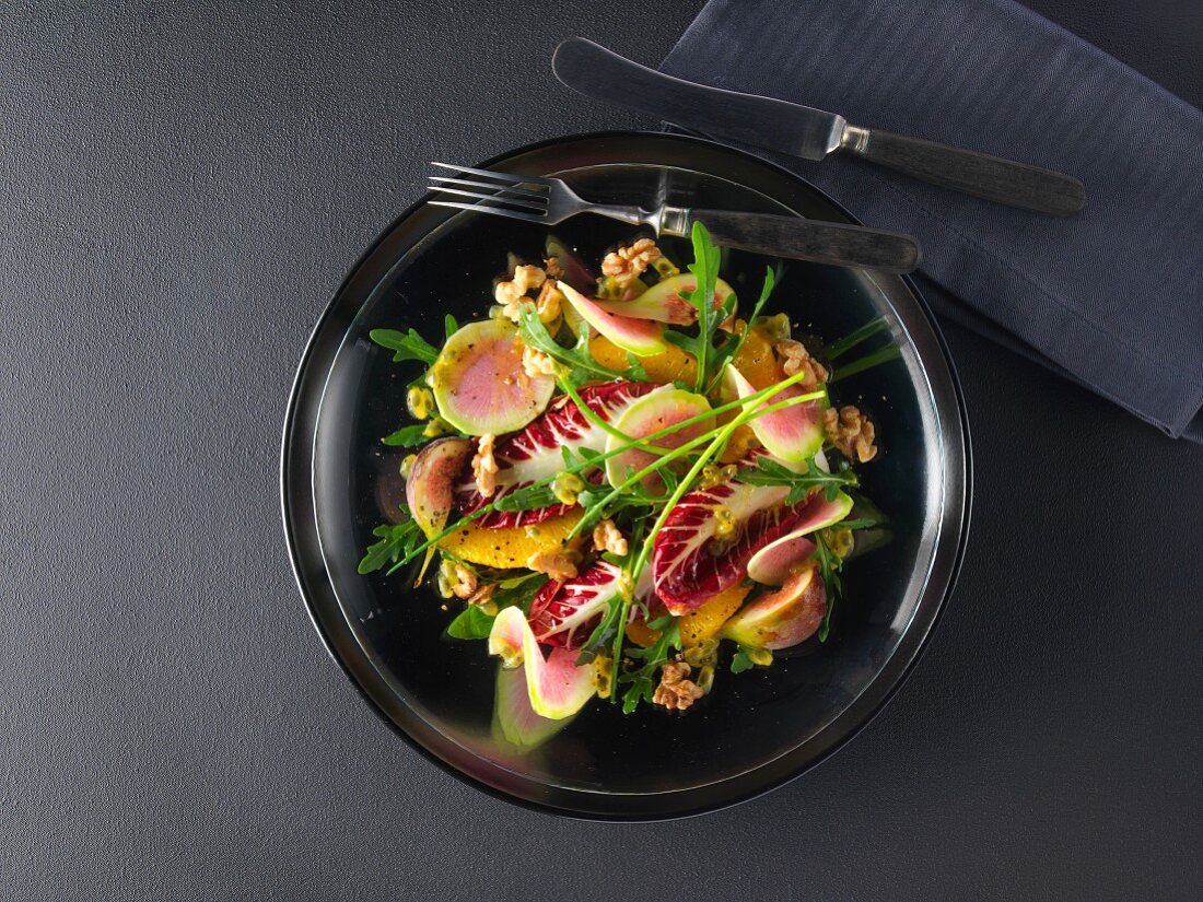 Mixed leaf salad with colourful radishes, oranges, figs, walnuts and passion fruit