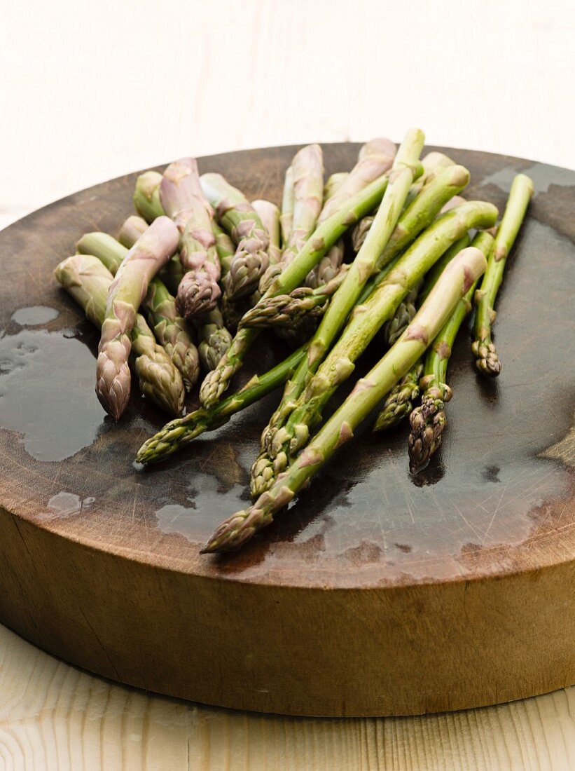 Fresh green asparagus on a round wooden board