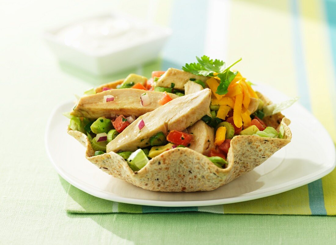 Colourful vegetable salad with chicken breast in a flatbread basket