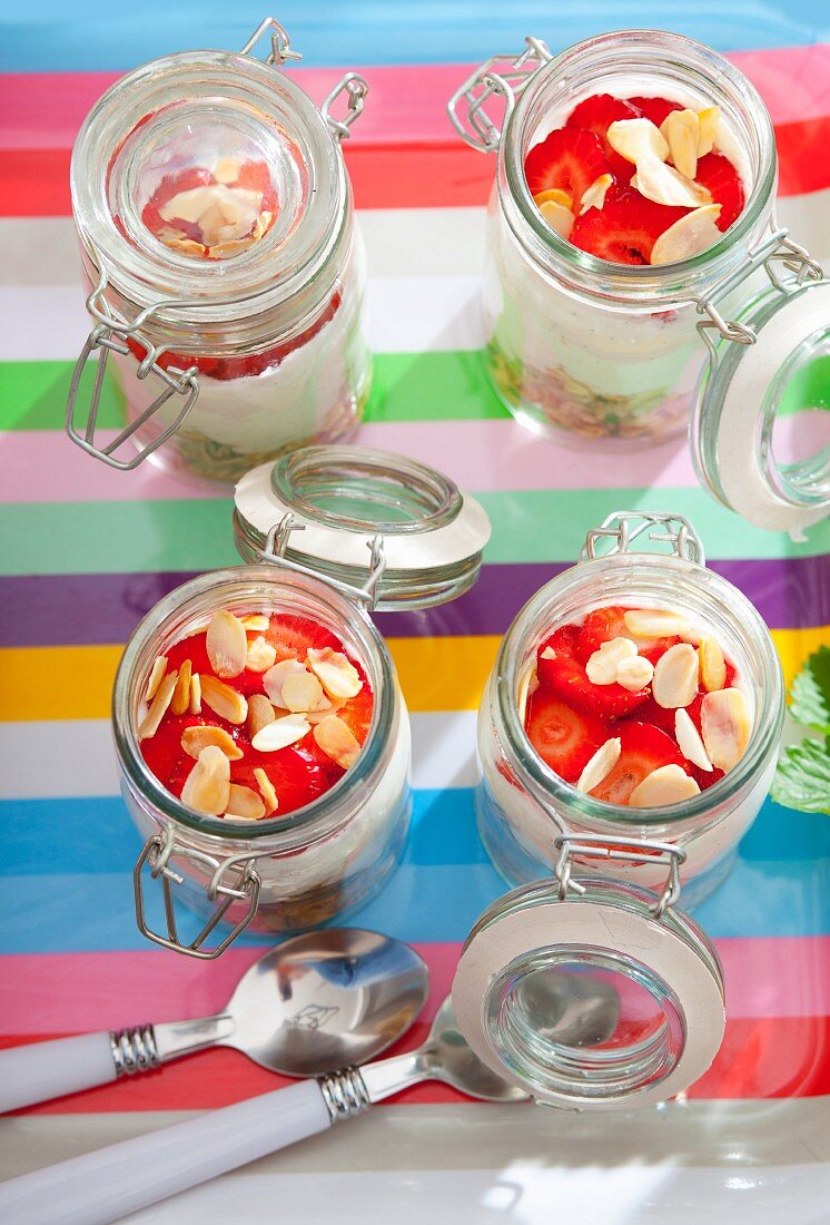 Zutaten für Müsli in vier Gläsern: Haferflocken, Vanillejoghurt und Erdbeeren