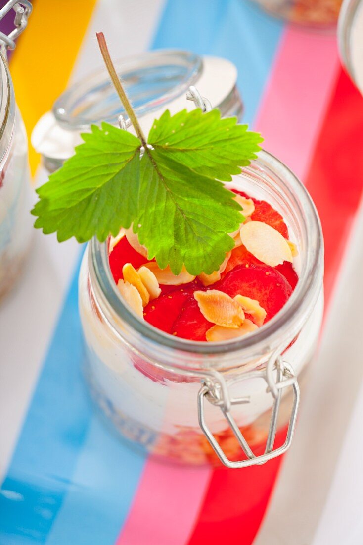 Zutaten für Müsli in einem Glas: Haferflocken, Vanillejoghurt und Erdbeeren