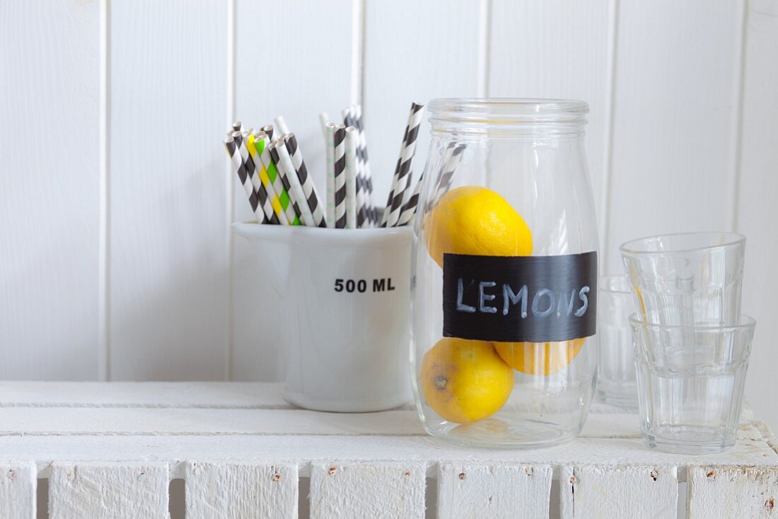Zitronen in einem Glas, Strohhalm und Wassergläser