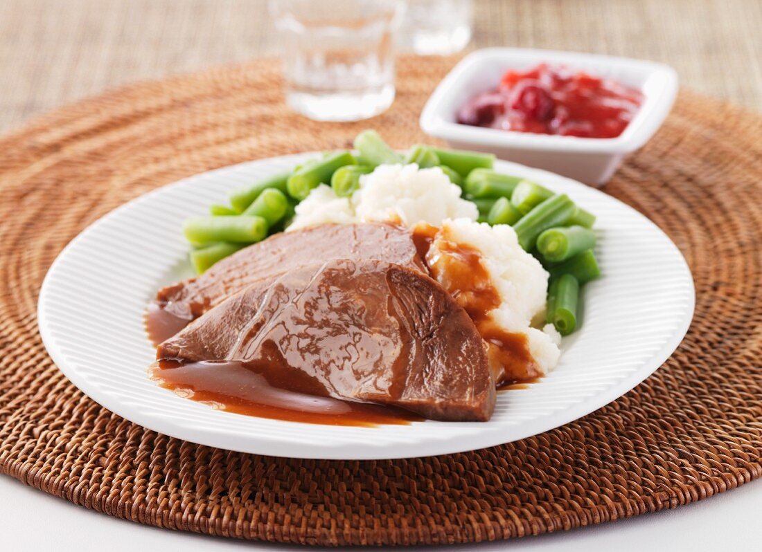 Slices of roast beef with mashed potato and green beans