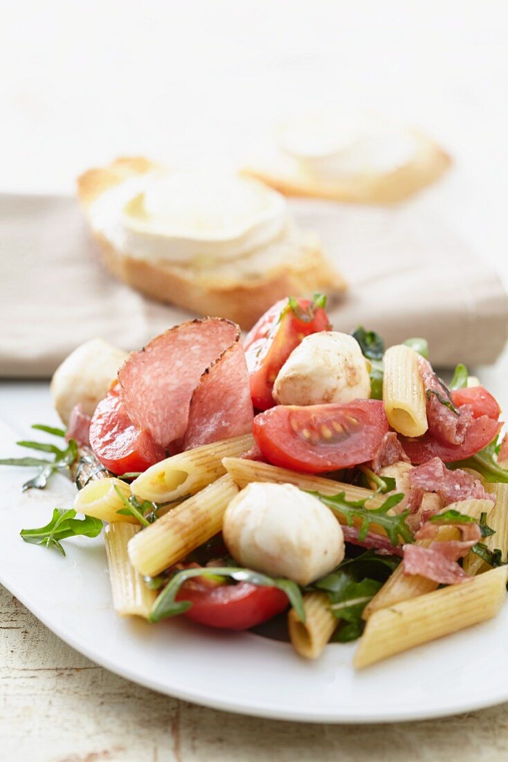 Pasta salad with tomatoes, salami, mozzarella and rocket