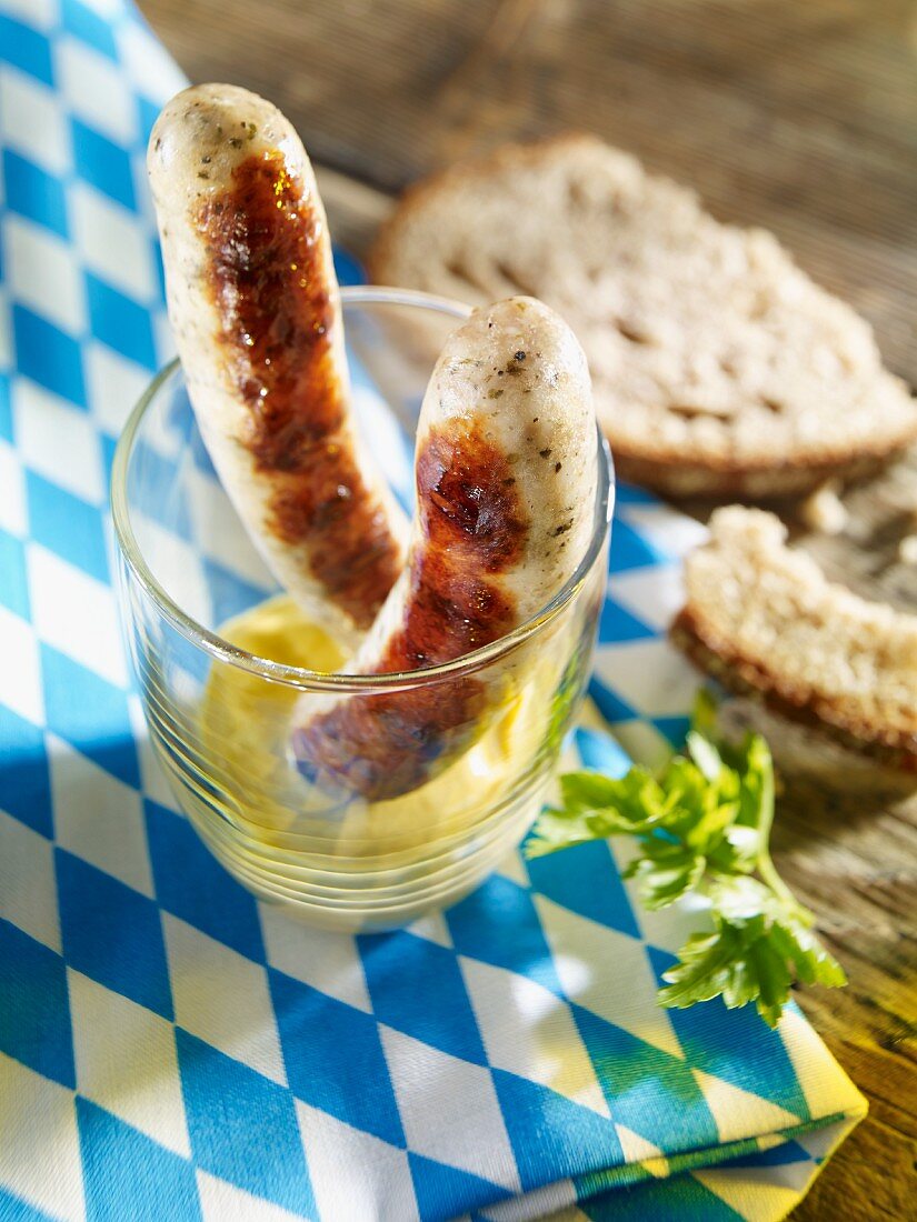 Zwei Rostbratwürstchen im Glas auf Senf