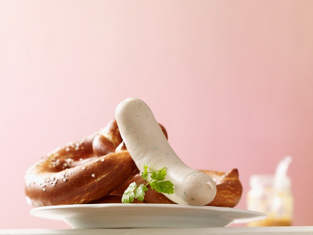 Pretzels and a white sausage; in the background a jar of mustard