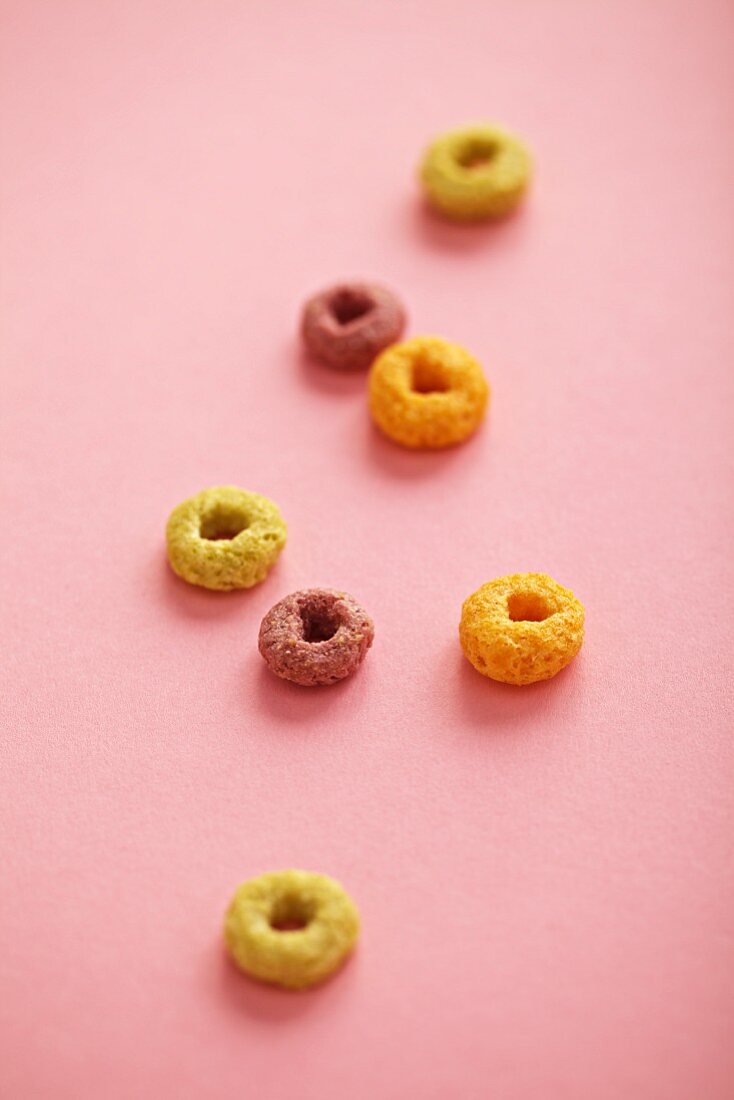 Pieces of breakfast cereal on a pink surface