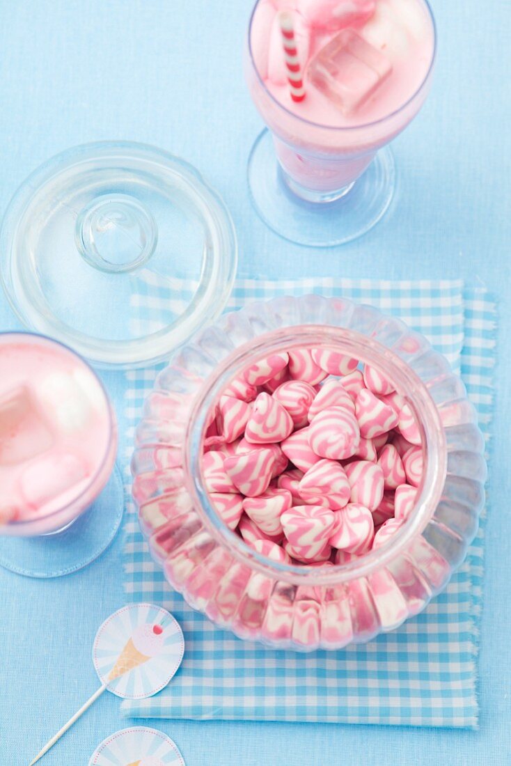 Glas mit rosa-weiss gestreiften Bonbons und Erdbeermilchshake mit Marshmallows