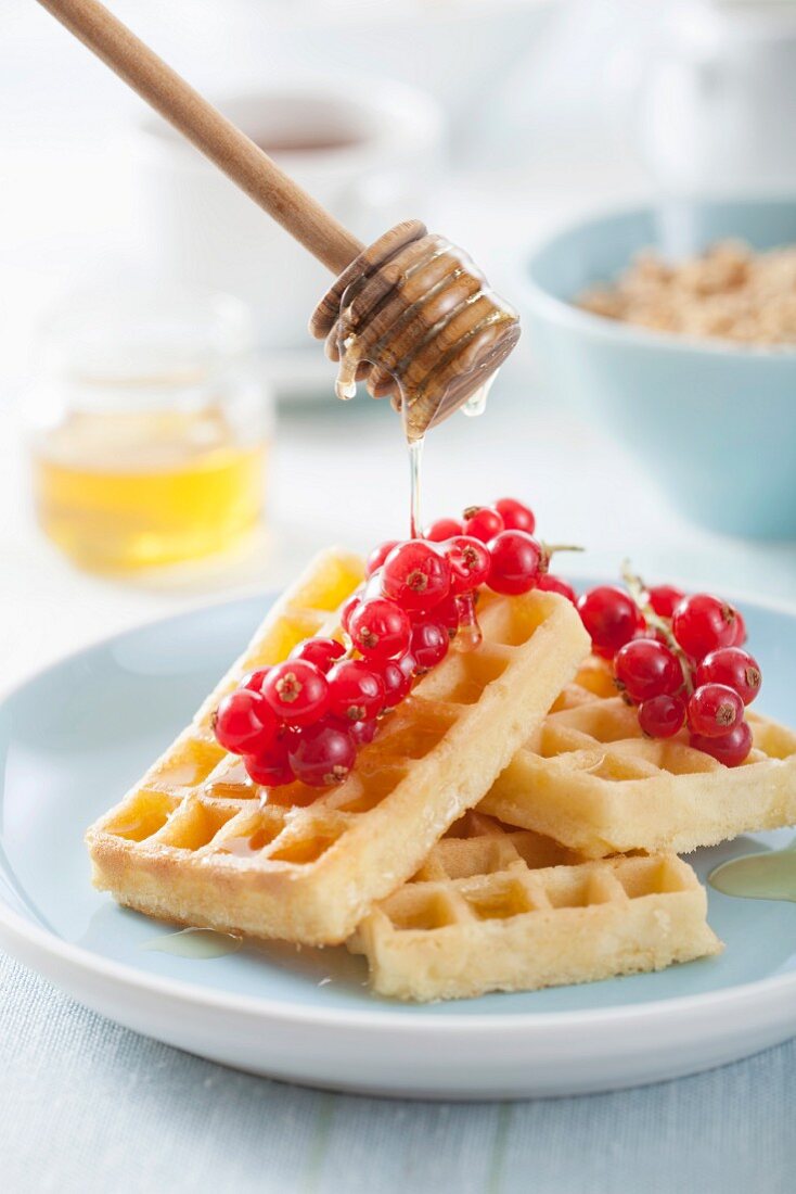 Waffles with redcurrants being drizzled with honey