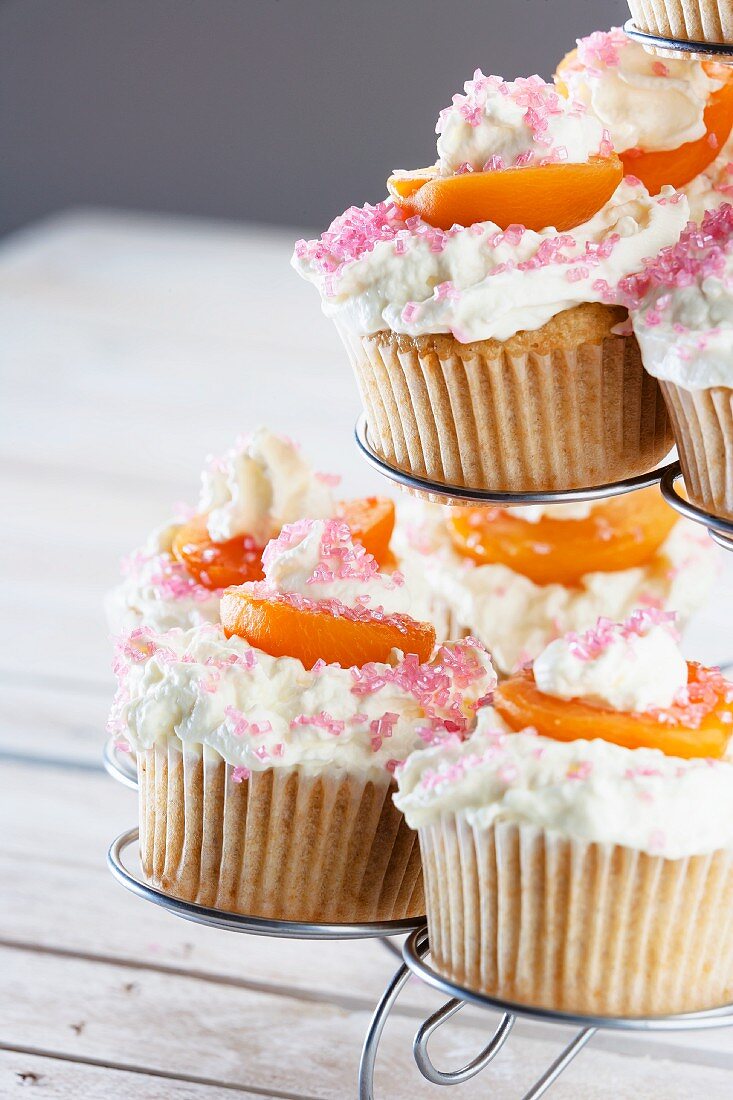 Cupcakes im Ständer mit Cremehaube, Aprikosen & Zuckerstreuseln