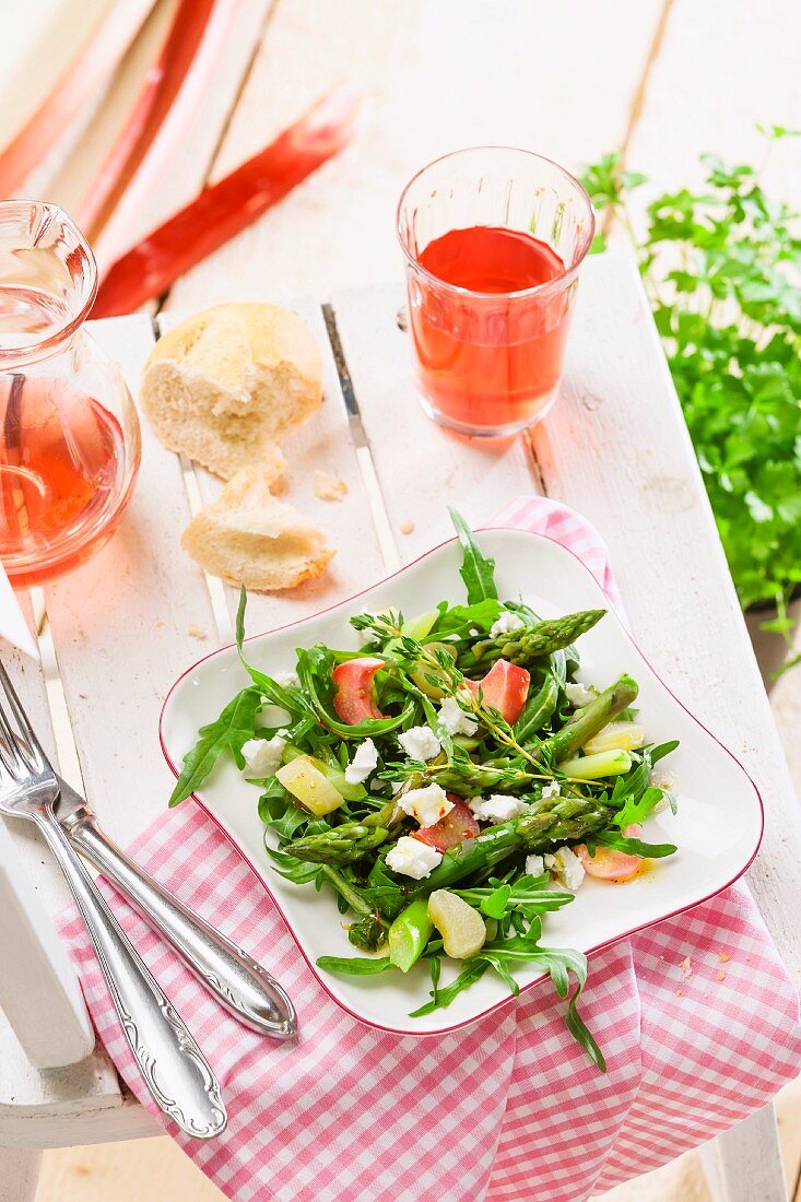 A spring salad of asparagus, rhubarb and rocket on a table outdoors