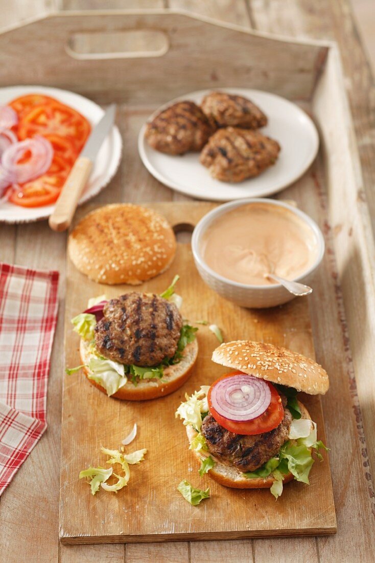Home-made burgers with burger constituents on a wooden tray