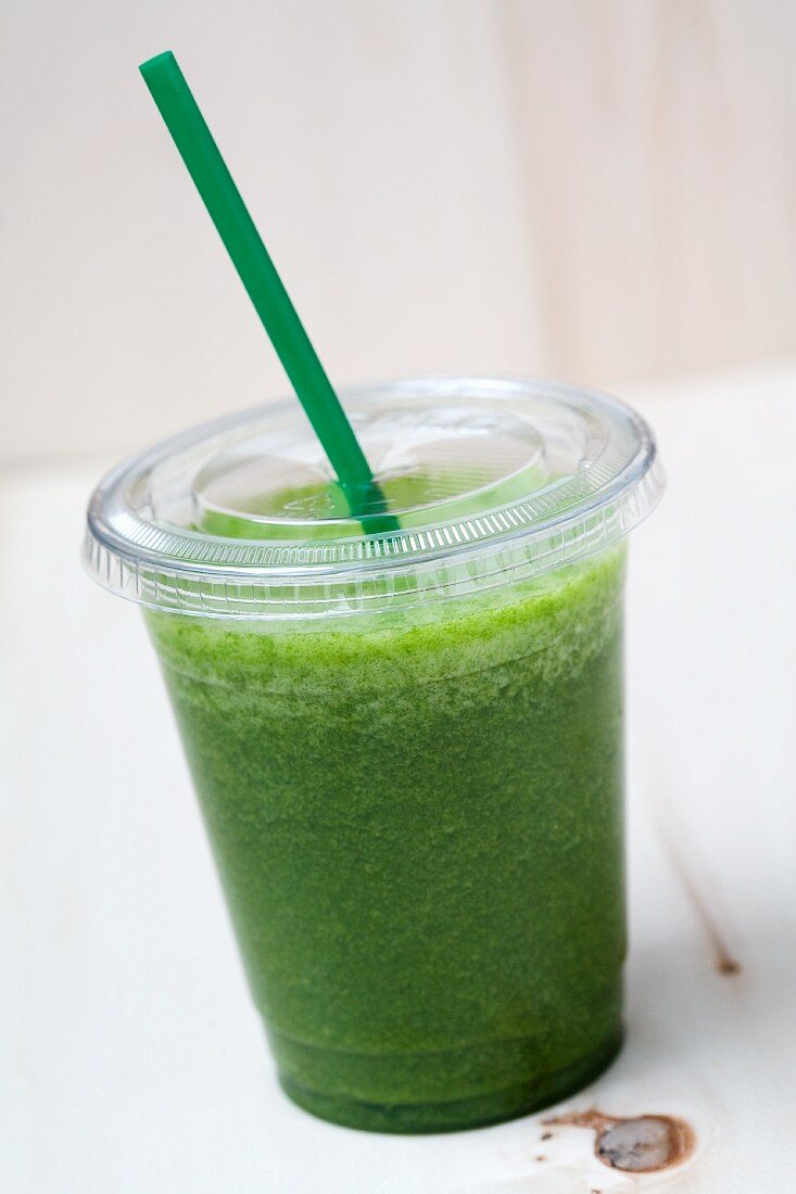 A green smoothie made with spinach, lamb's lettuce, apple, banana and apple mint in a plastic cup