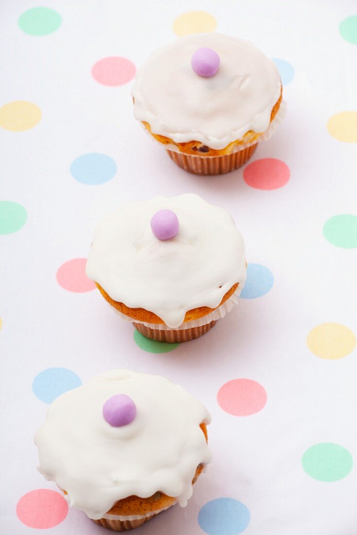 Three mini cupcakes decorated with sugar icing and marzipan balls