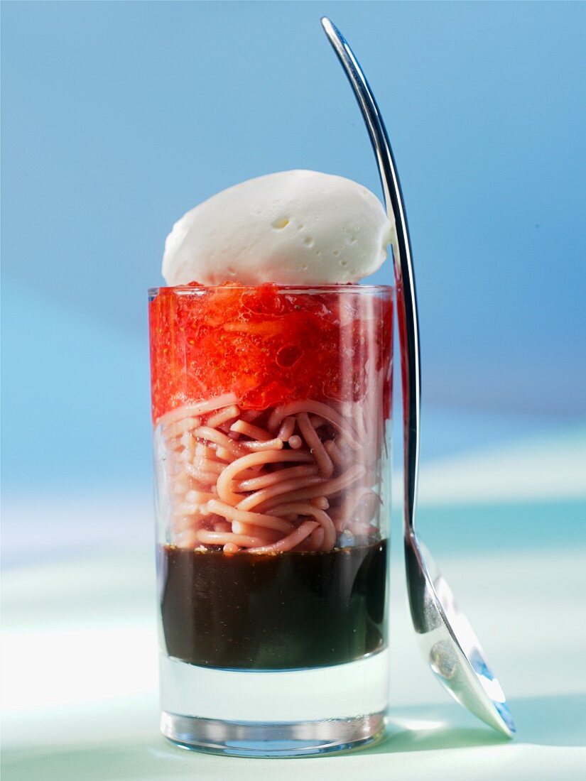 A layered dish of spaghetti with strawberries on balsamic syrup