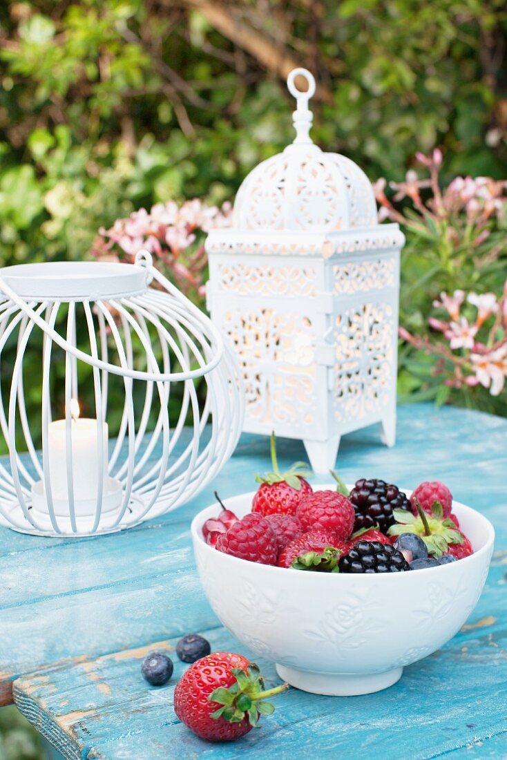 Fresh berries in a bowl on a garden table with lanterns