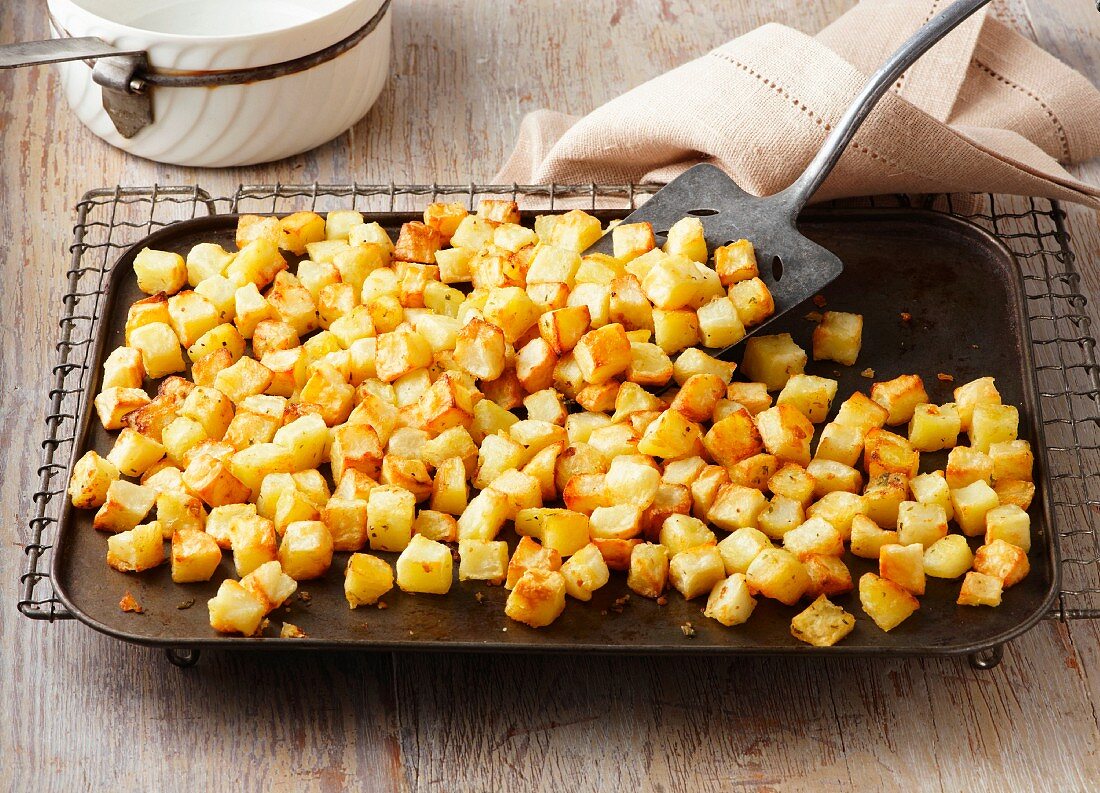 Parmentier potatoes on baking sheet and wire rack. Maris Piper potatoes roasted in garlic and rosemary butter