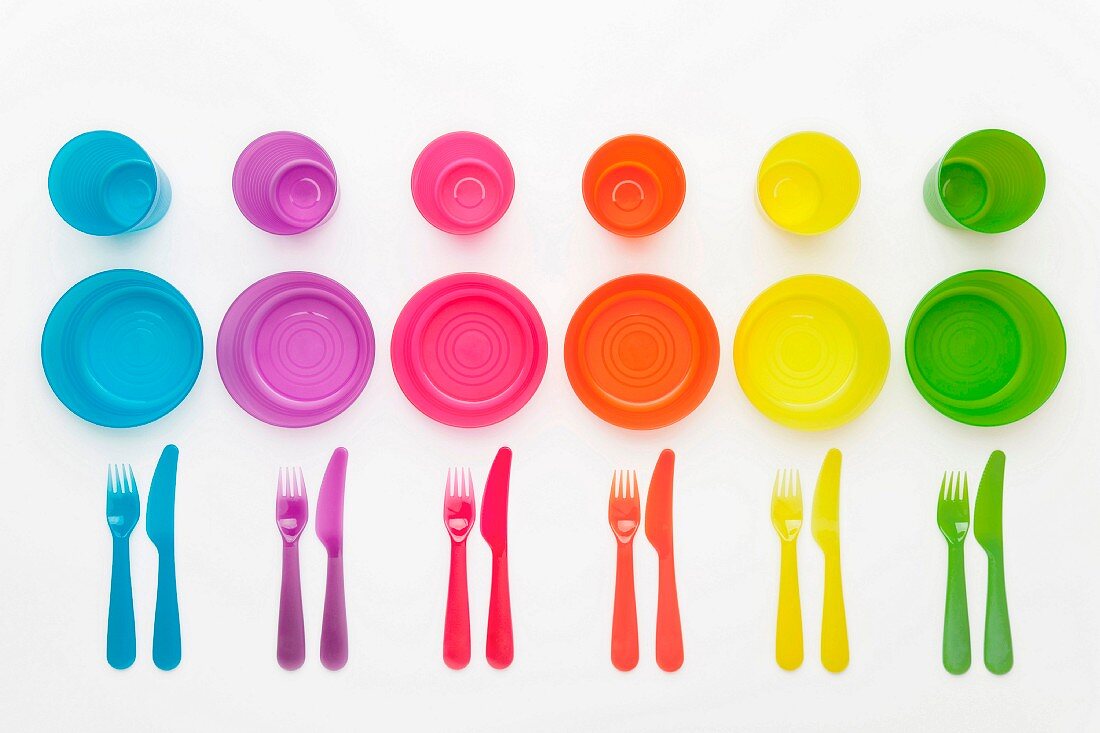 Colourful plastic plates, cups, bowls and cutlery