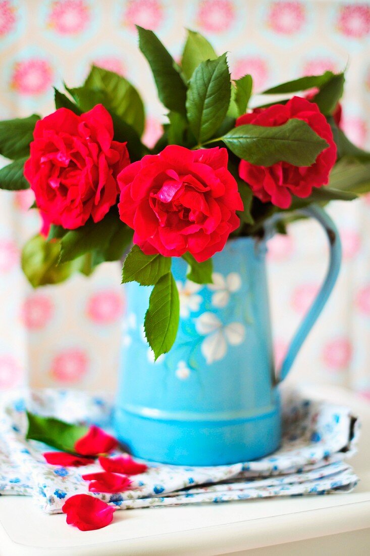 Rote Rosen in einer blauen Emailkanne