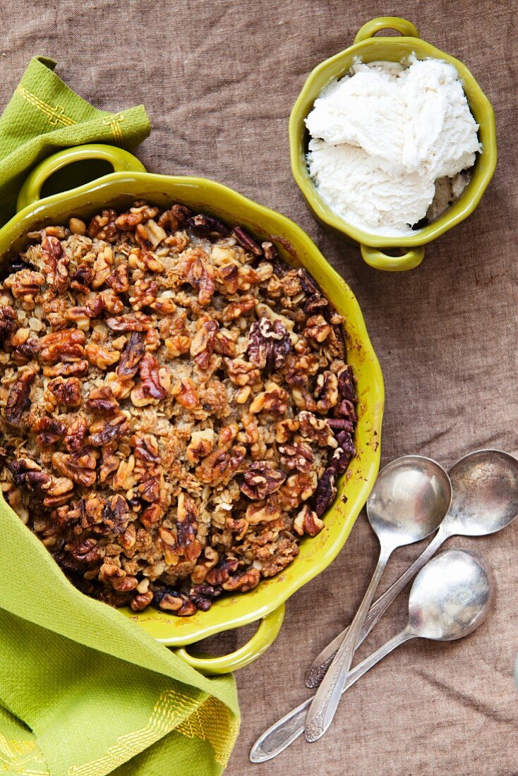 Glutenfreier Apple Crisp in Auflaufform und eine Schüssel Vanilleeis