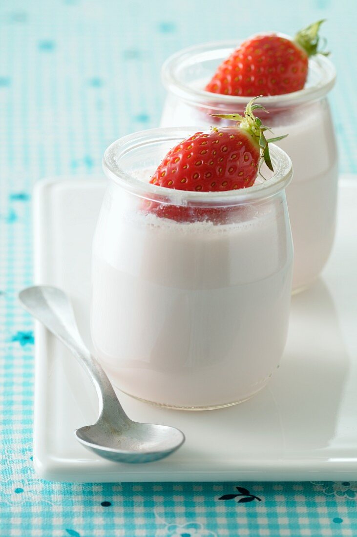 Natural yoghurt in glass pots, garnished with fresh strawberries