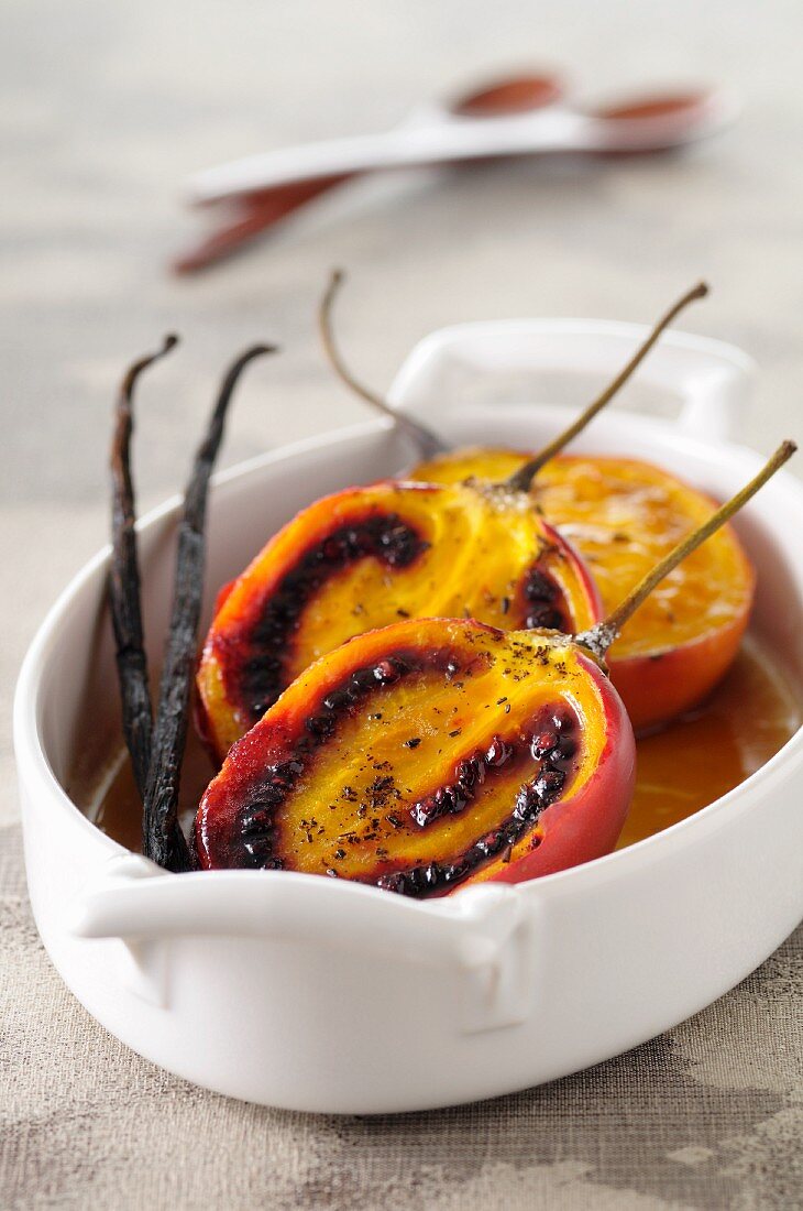 Baked tamarillos with vanilla pods in a casserole dish