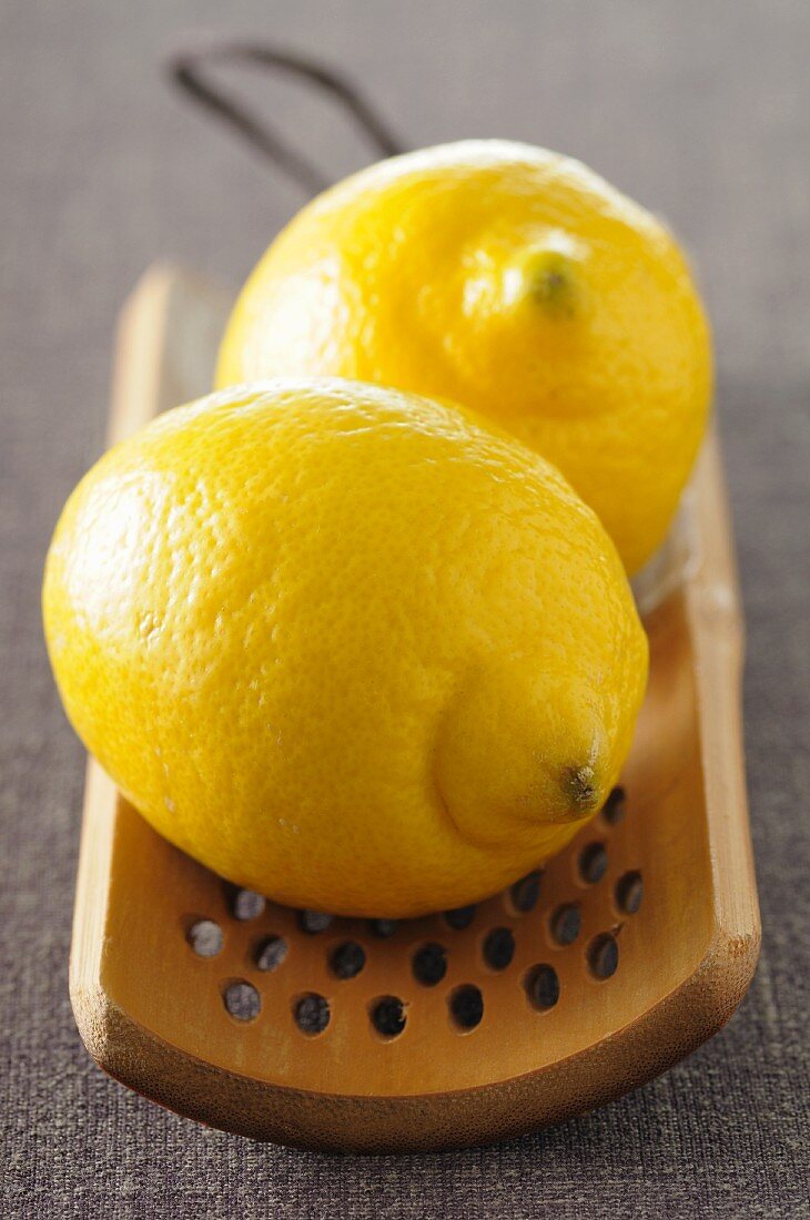 Two lemons on a wooden grater