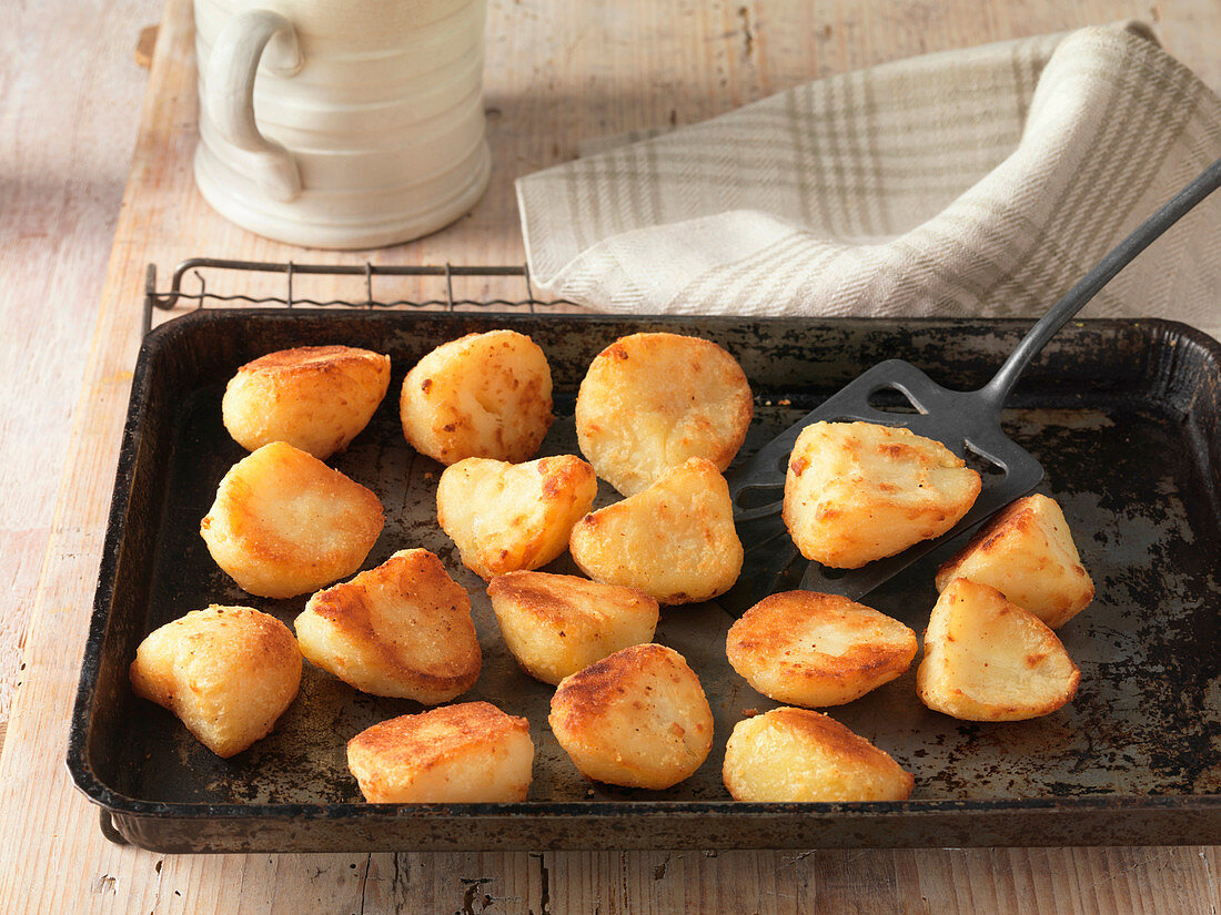 Beef dripping roast potatoes on baking tray and wire rack